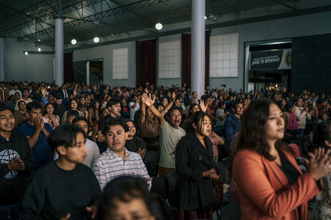 A lively worship service with diverse attendees engaged in prayer at a church in Mexico.